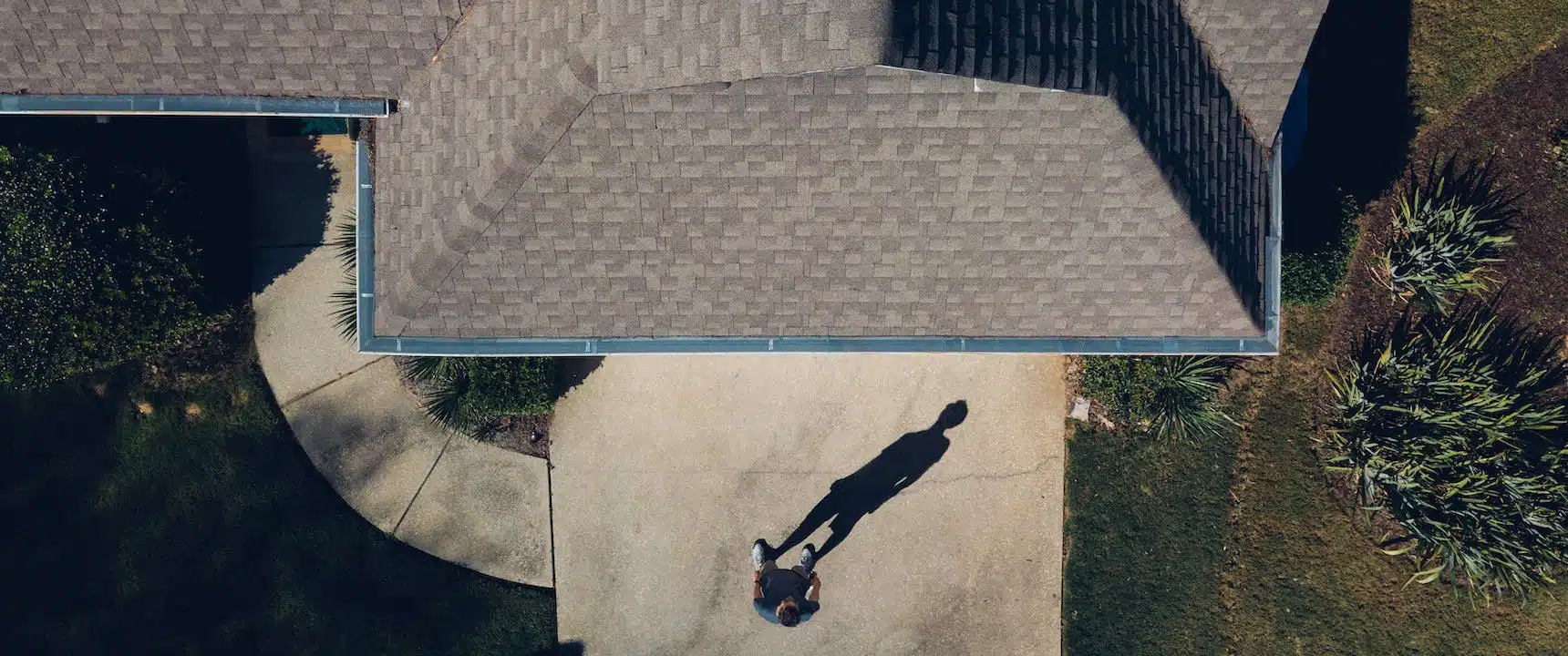 Aerial view of a person walking near a house casting a long shadow